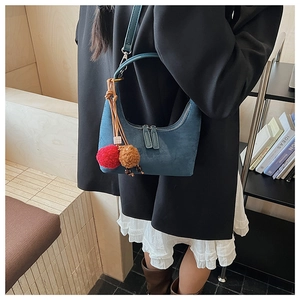 Détail du sac hobo en daim bleu foncé avec double fermeture éclair et pompons décoratifs