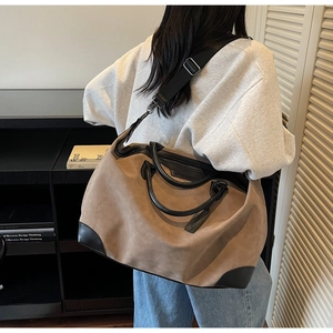 Vista dettagliata di una grande borsa tote in camoscio kaki con finiture in pelle nera e tracolla