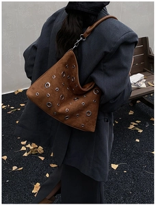 Sac hobo en daim marron avec rivets argentés porté par un mannequin en style automne