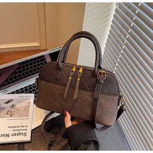 Close-up of diamond quilted stitching and dual zippers on a brown faux leather handbag