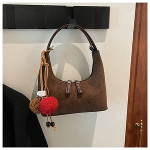 Détail du sac à bandoulière en daim marron foncé avec double zip et pendentif en peluche
