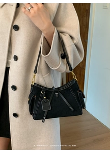 Detail of vintage black suede shoulder bag with white contrast stitching and gold hardware