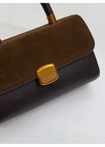 Detail of dual-material splicing handbag with dark brown suede and retro golden metal lock