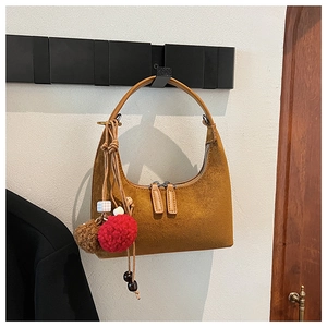 Détail du sac demi-lune en daim fauve avec double fermeture éclair et pompon décoratif