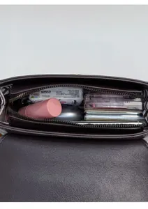 Top view of compact brown leather square bag showing interior storage with daily essentials