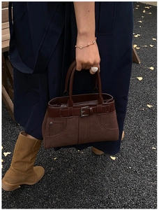 Detail of dark brown matte suede and smooth leather bag with retro decorative buckles