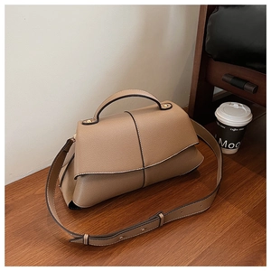 Detail of brown lychee grain leather puzzle bag with top handle and gold hardware