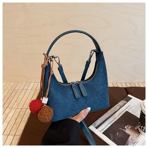 Détail du sac hobo en daim bleu avec double fermeture éclair et pompons en peluche