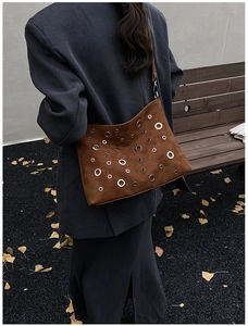 Vue détaillée d'un sac bandoulière en daim marron avec œillets métalliques style vintage