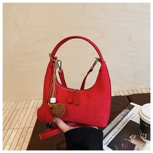 Gros plan du sac sous le bras en daim rouge avec pompons et double fermeture