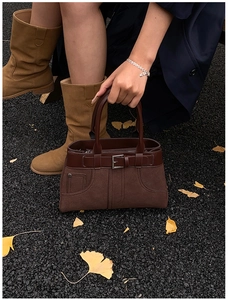 Detail of vintage matte suede handbag with leather accents and metal buckle outdoors