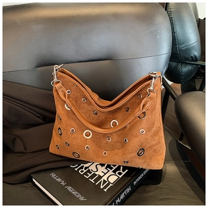 Détail du sac bandoulière en daim marron avec œillets métalliques sur cuir noir