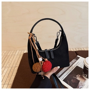 Détail du sac hobo croissant noir avec pompons en peluche et poignée ronde de près