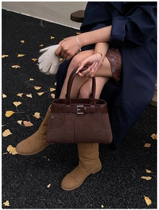 Detail of dark brown vintage matte leather handbag with silver buckle and autumn styling