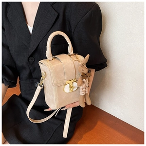 Detail of a beige flap handbag with gold twist lock and a brown plaid bunny charm