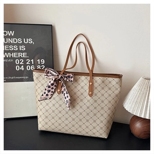 Détail d'un cabas beige avec motif géométrique, anses en cuir et foulard léopard en soie