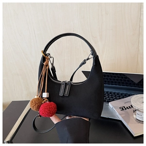 Détail du sac hobo en daim noir avec double fermeture éclair et pendentif décoratif en peluche