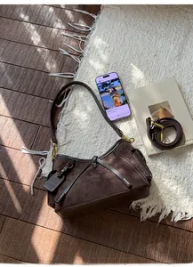 Detail of dark brown suede hobo bag featuring white contrast stitching and antique hardware