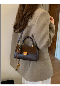 Detail of retro color-block handbag with gold hardware and leather tassel on a model