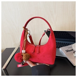 Vue détaillée du sac demi-lune en daim rouge avec double fermeture éclair et pompon décoratif