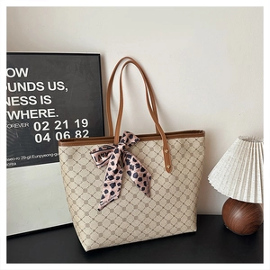 Détail du sac cabas beige avec poignées en cuir marron et foulard en soie motif léopard