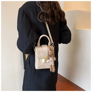 Detail of light beige structured square bag with gold lock and cute rabbit charm
