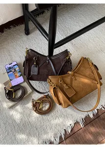 Close-up of vintage suede Boston bags with gold hardware and leather brand tags on a rug