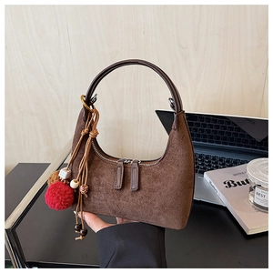 Gros plan détaillé du sac hobo en daim marron avec pampille ethnique et double fermeture