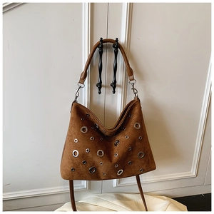 Détails du sac hobo en daim marron avec des œillets métalliques argentés et rivets décoratifs