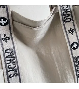 Detailansicht der beigen Tragetasche mit Jacquard-Gurt und dem Shichaobag-Logo