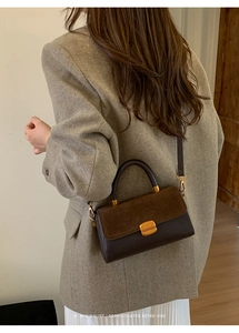 Detail of vintage brown two-tone crossbody bag with gold lock and sleek leather finish