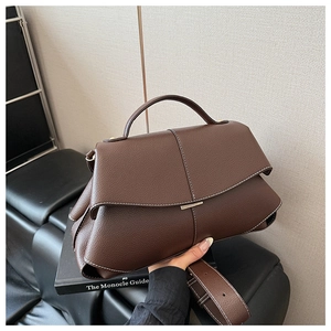 Detail of dark brown pebble leather shoulder bag with white contrast stitching and clasp