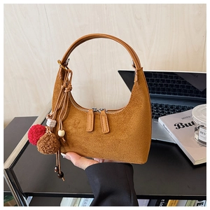 Détail d'un sac hobo en daim marron avec double fermeture éclair et charm décoratif