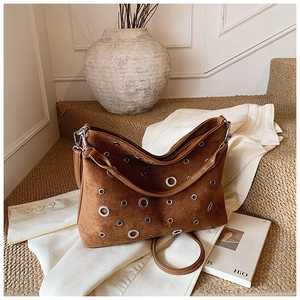 Détail d'un sac à bandoulière en daim marron avec œillets argentés et large sangle