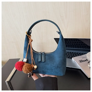 Détail de la texture en daim bleu marine du sac hobo avec breloque pompon décorative