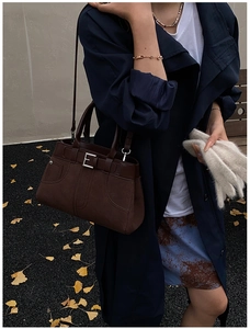Detail of dark brown leather crossbody bag with silver buckle and autumn styling