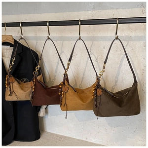 Detail view of four earth-toned suede hobo bags with retro charms on a metal display