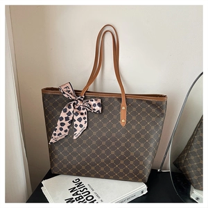 Détail d'un sac cabas marron à motifs avec anses en cuir et foulard léopard décoratif