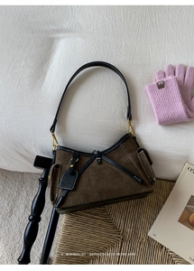 Close-up of brown suede shoulder bag with black leather trim and gold hardware details