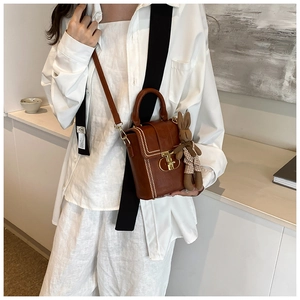Close-up of brown vintage crossbody bag with white stitching and rabbit plush charm