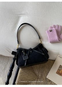 Detail of black vintage tote with contrast stitching and branded leather tag in home setting