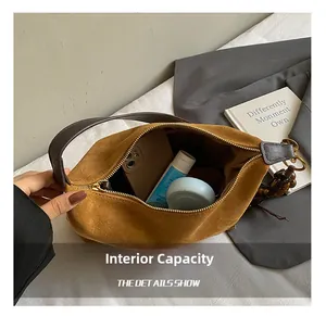 Macro view of brown suede shoulder bag interior with phone and cosmetic items