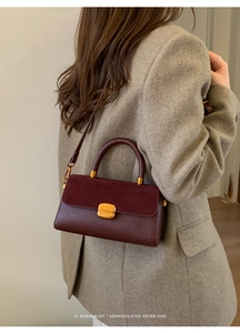 Detail of vintage burgundy leather handbag featuring suede flap and gold twist-lock buckle