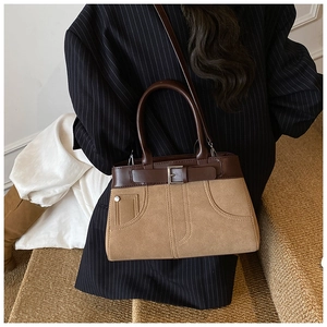Macro detail of retro dual-tone handbag with matte brown suede and contrast stitching