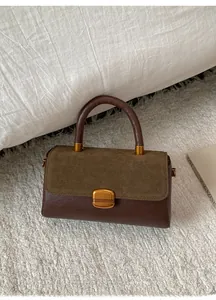 Detail of vintage crossbody bag with contrast suede flap and antique gold buckle clasp