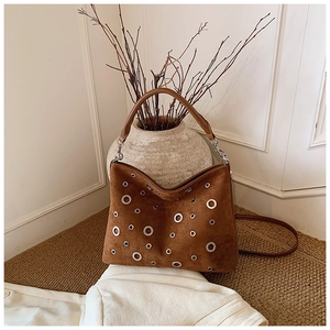 Gros plan du sac cabas en daim marron avec œillets métalliques et double bandoulière