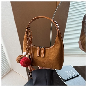 Détail du sac croissant en daim marron avec pompon en peluche et perles décoratives