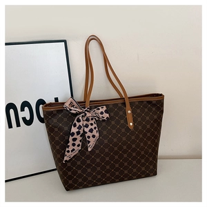 Détail d'un grand sac cabas marron foncé avec un ruban léopard rose noué sur l'anse