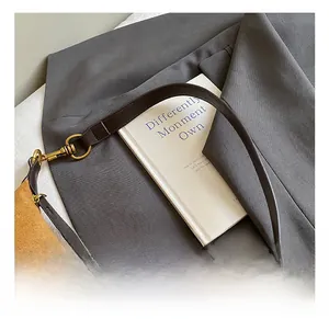 Detailed macro view of the brown suede bag featuring premium golden metal rings and leather strap