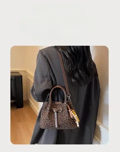 Close-up of leopard print suede bucket bag with wooden bead charm and brown leather straps